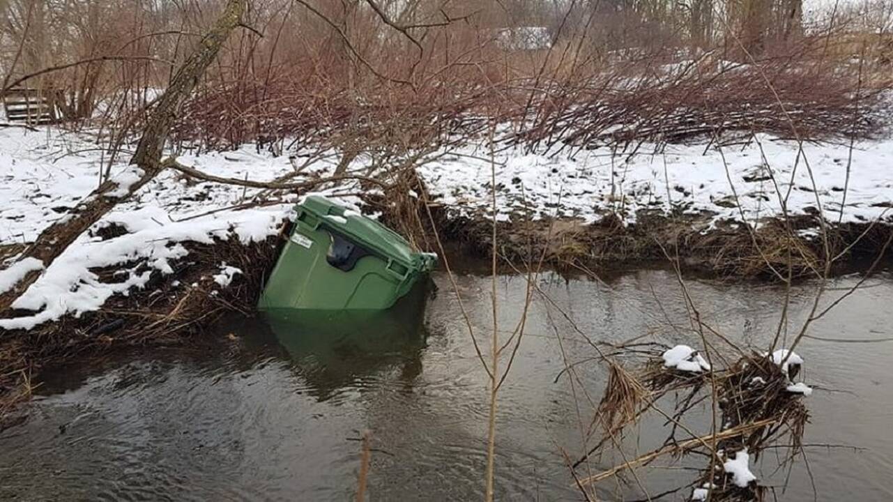 Pasilinksmino: kažkam buvo smagu įstumti šiukšliadėžę į upelį.
