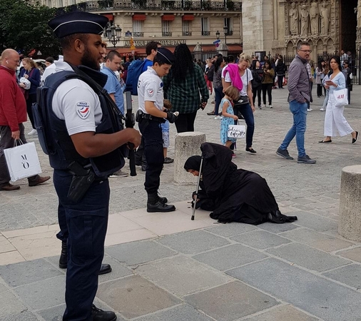 Realybė: ginkluota policija ir valkatos prie Paryžiaus katedros.